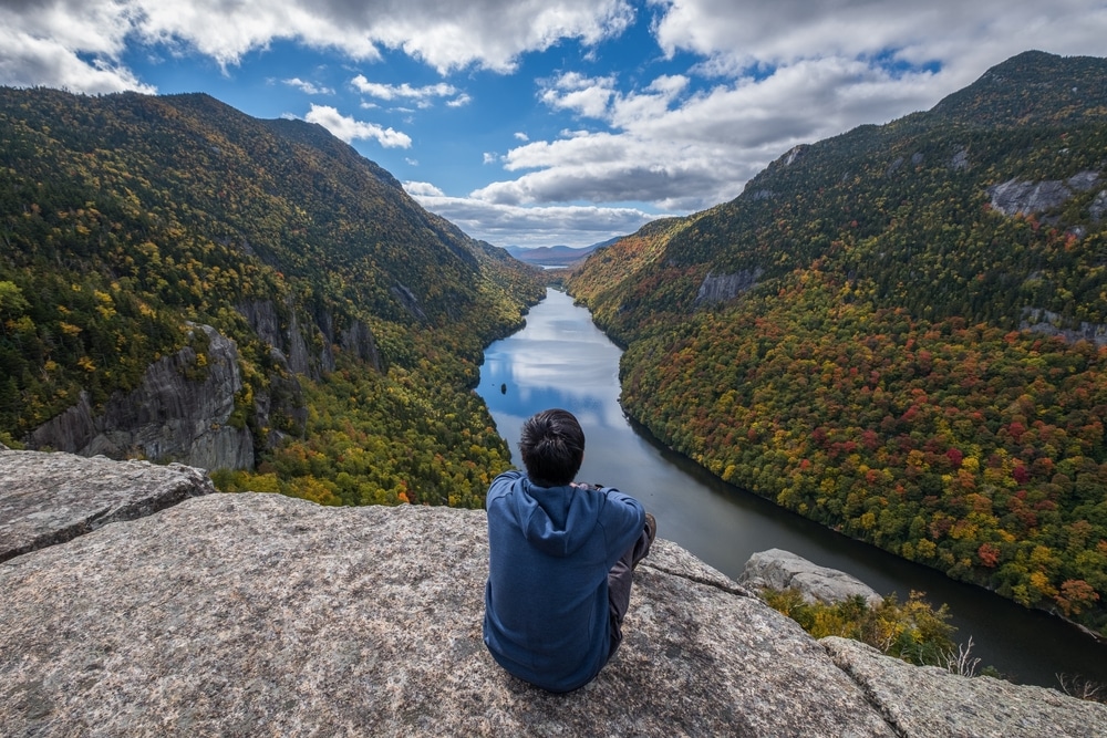A man enjoying a great view in the Adirondacks after hiking, which is one of the most popular things to do in the Adirondacks